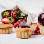 side view cupcakes with strawberry jam basil and fresh strawberry on white background