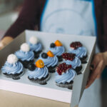 crop-woman-holding-box-with-muffins